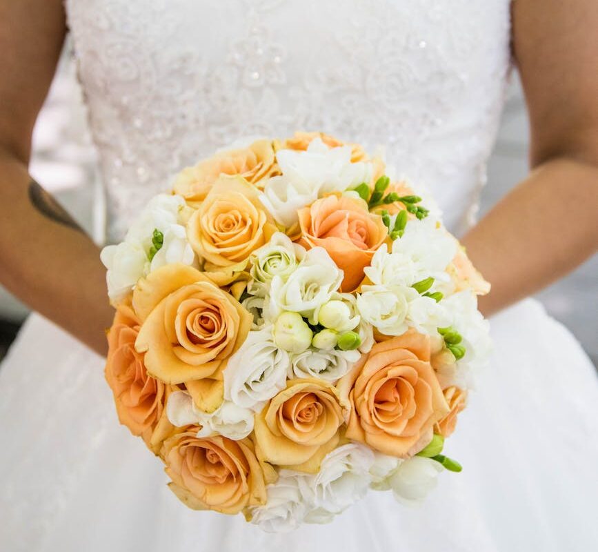 person in white bridal gown holding flower bouquet