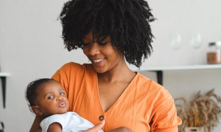 an afro haired woman carrying a baby