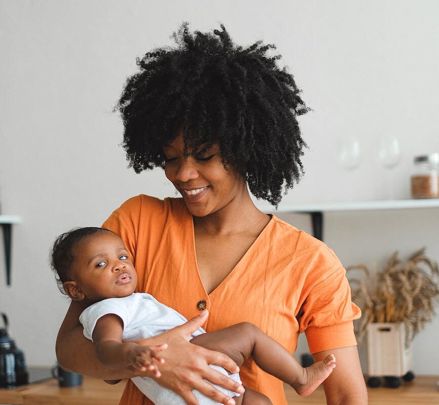 an afro haired woman carrying a baby