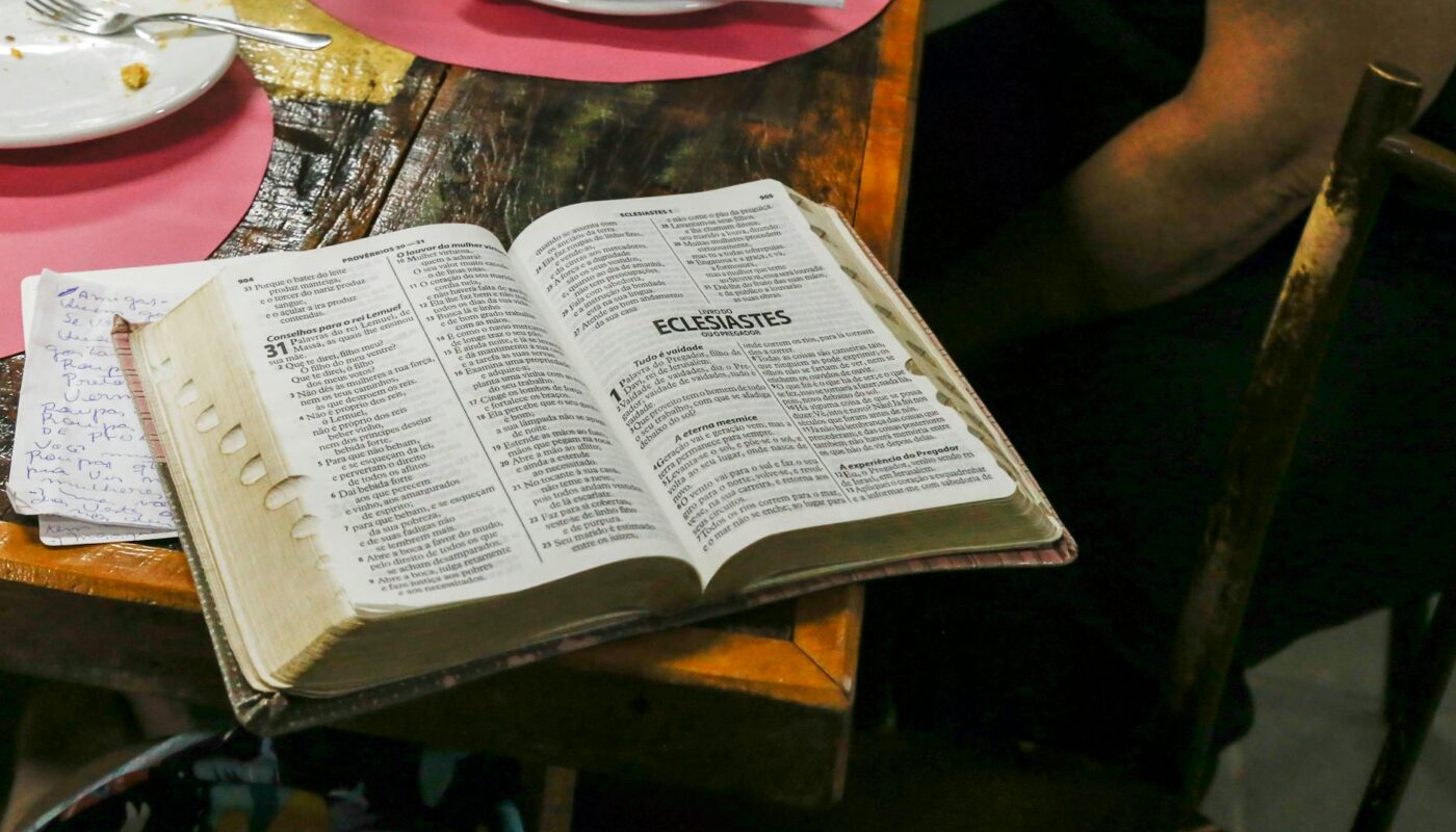photo of opened bible book on brown table