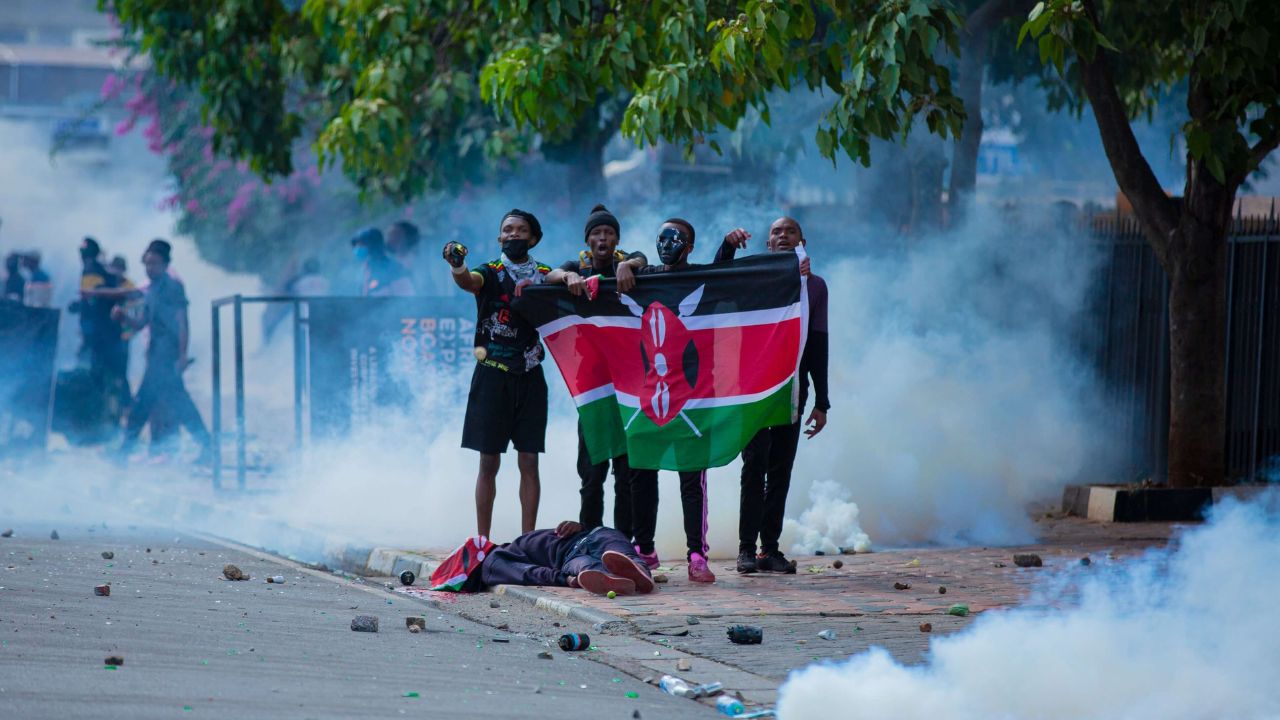 Protesters in Kenya hold up a flag next to a dead body, a victim of political demonstrations.