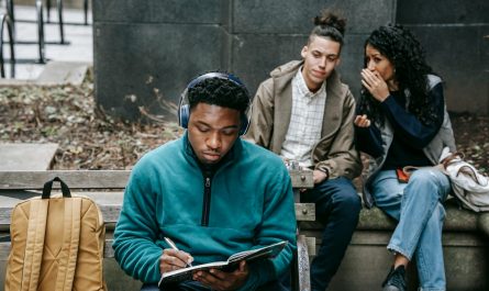 multiracial students gossiping about black man with notepad