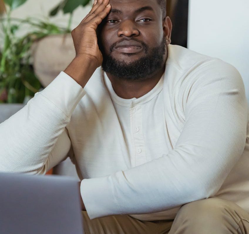 tired black man leaning on hand and looking away