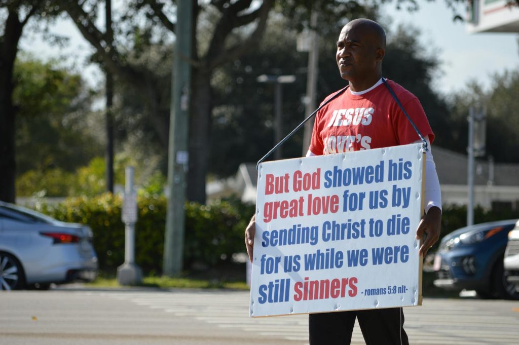 man holding a banner with a bible quote