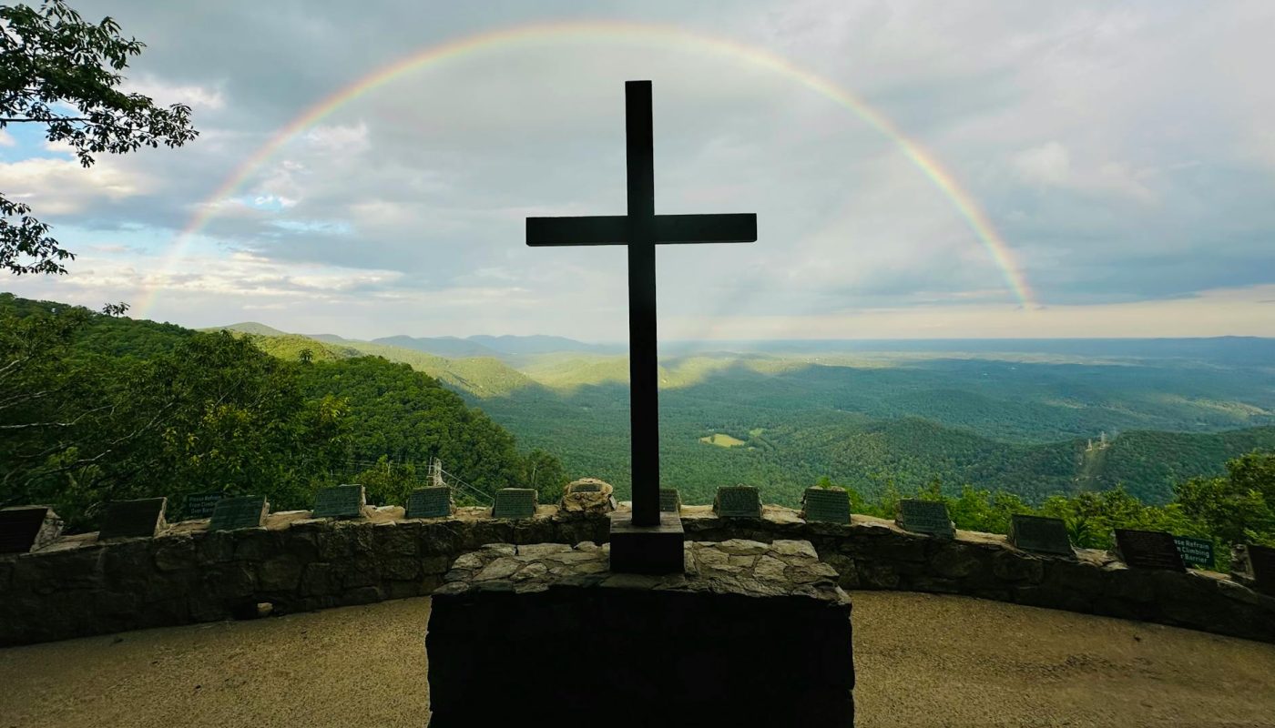 scenic mountain view with cross and rainbow