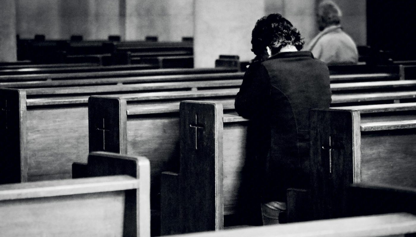 unrecognizable men praying in old catholic church