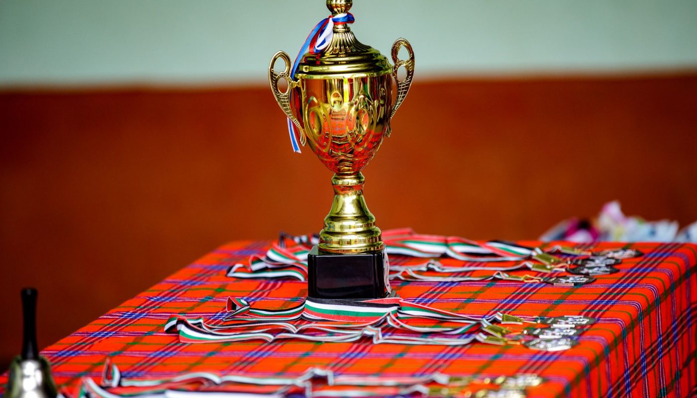 a gold trophy and medals on a table with a checkered cloth